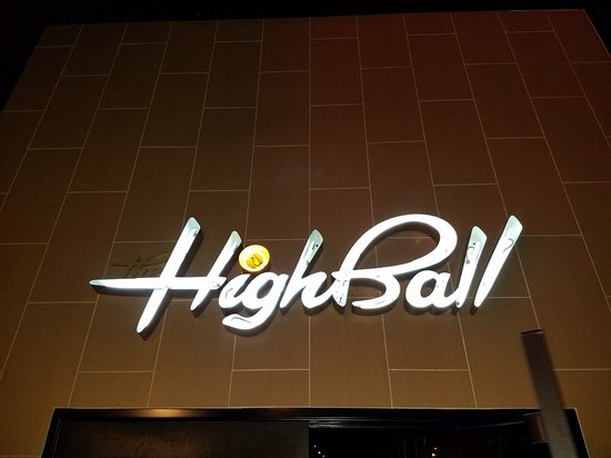 Hanging above a building entrance is a glowing sign in the shape of The Highball logo.