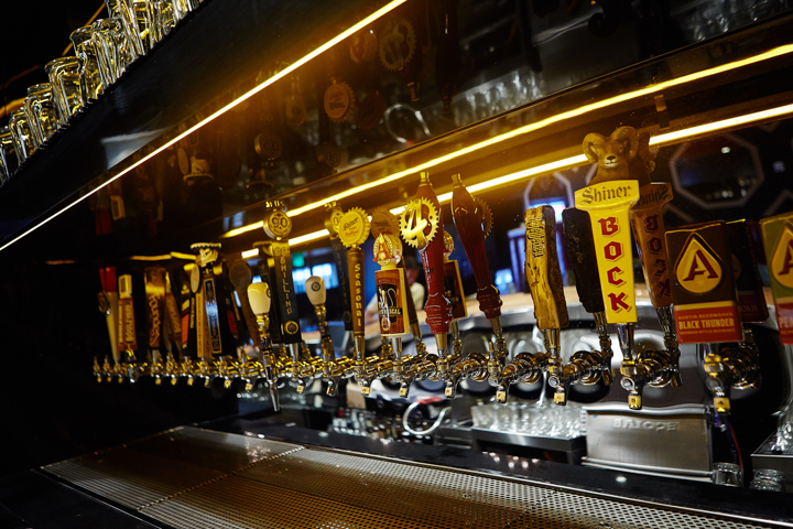 An angled shot of several bar taps for many different beers on draft.